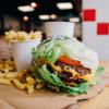 A close up of a five guys meal including a drink, fries and a lettuce leaf shell burger 